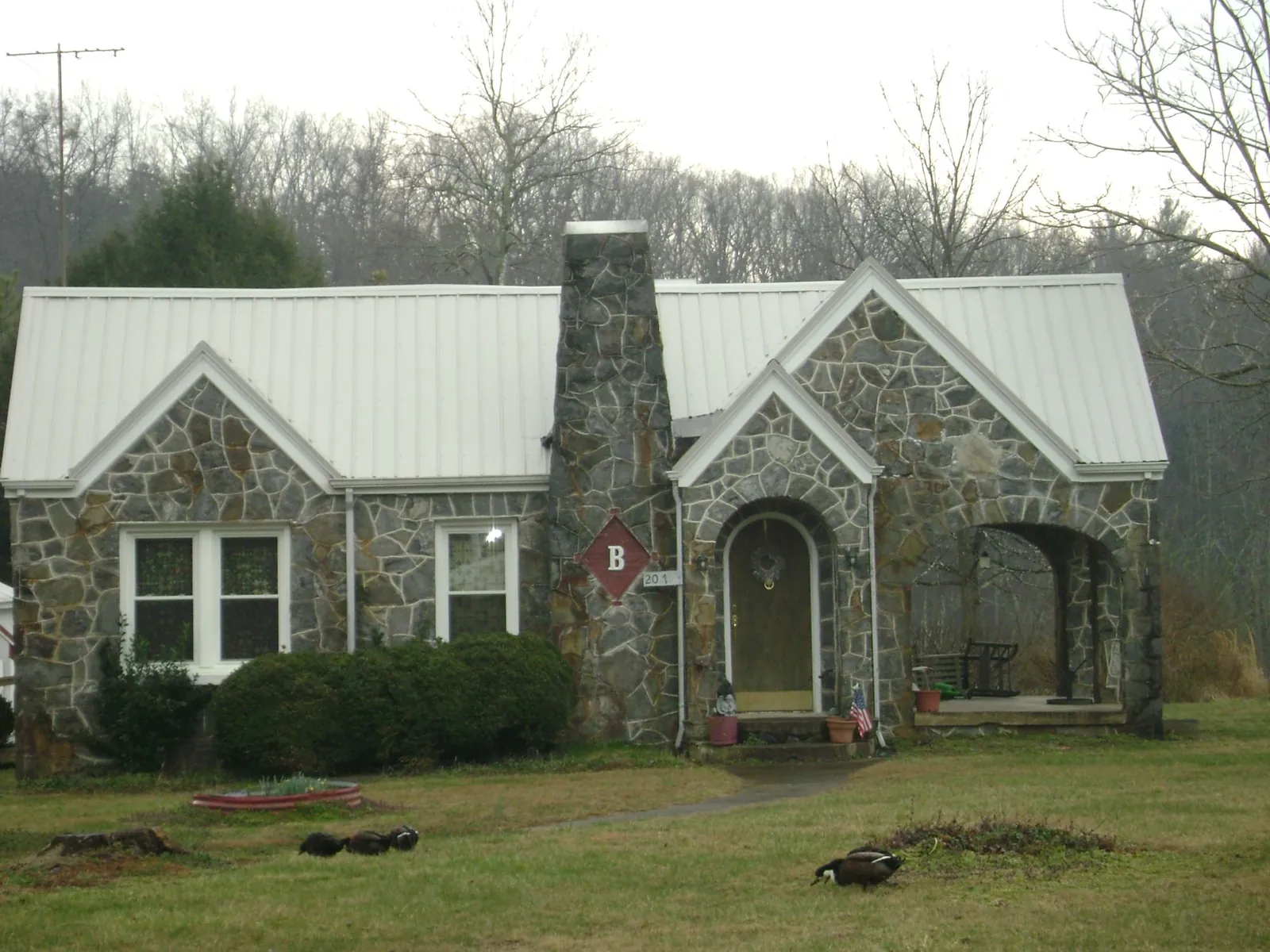 White metal roof on a stone cottage with steep gables in Holden