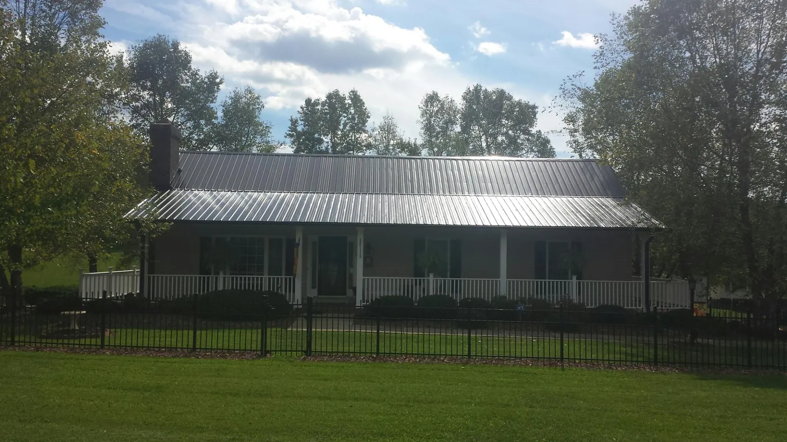 Gray metal roof on a brick ranch with a full width front porch — Gutter Guard Installation work by our crew in Holden